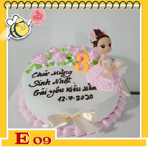 Bánh kem búp bê E09 váy hồng ngồi thẩn thơ trên nền trắng thắt nơ và hoa màu hồng nhạt dễ thương