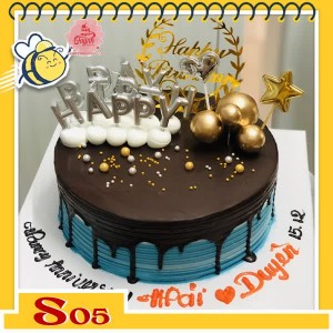 Bánh kem socola S05 phủ trên nền bánh xanh nhạt và cắm nhiều phụ kiện nến bi khung sinh nhật